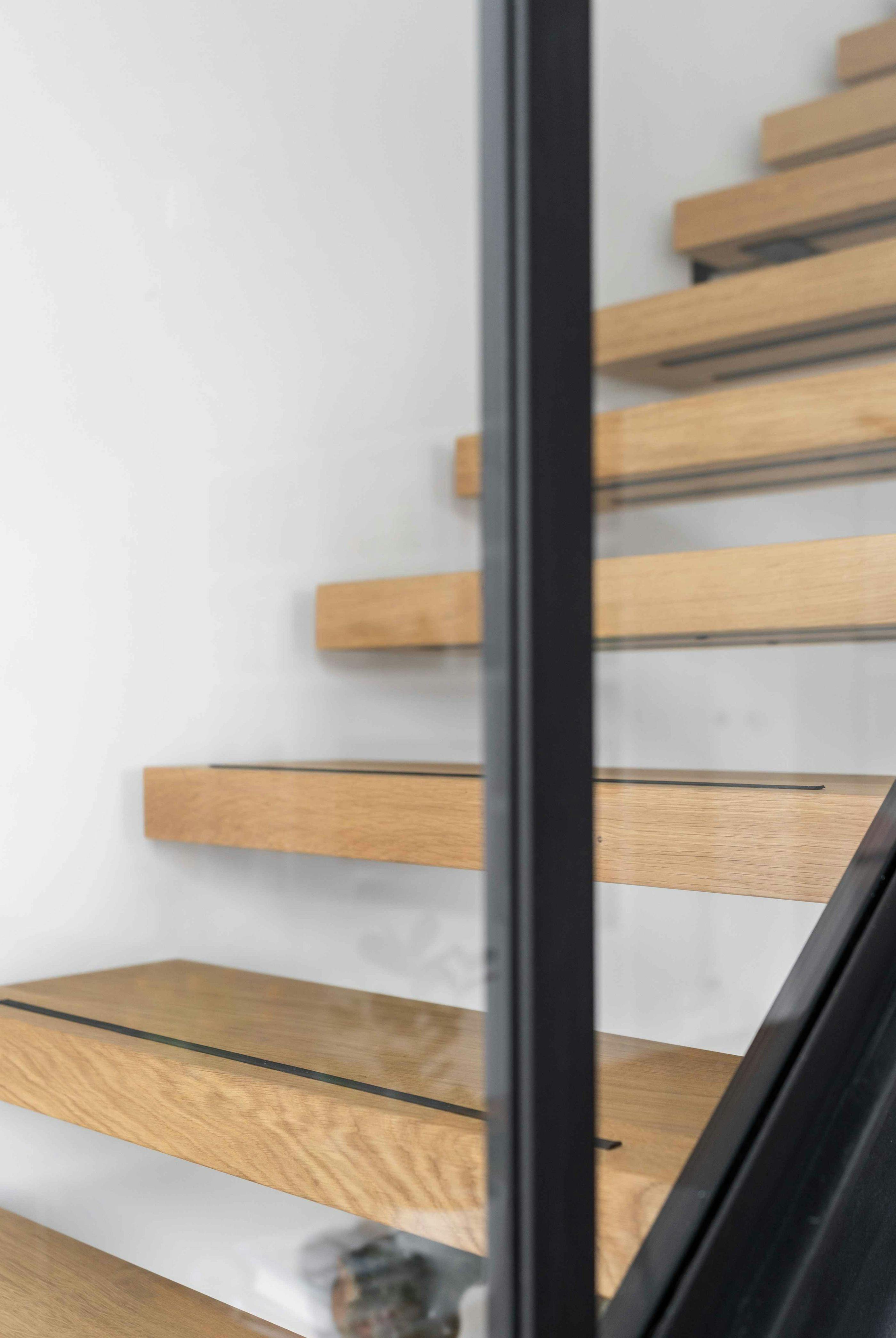 Twee stalen trappen met massief eiken treden en balustrades van staal en glas